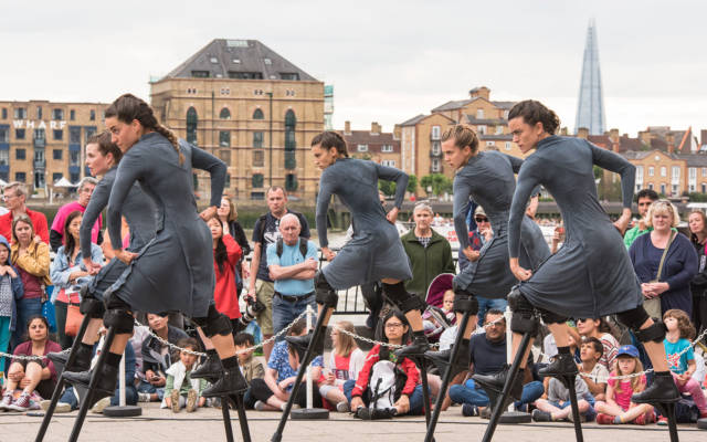 Mulier, Cia Maduixa, Dancing City, Canary Wharf, GDIF 2017. 5 women on stilts dance in front of a crowd. The shard and the river Thames are in the background.