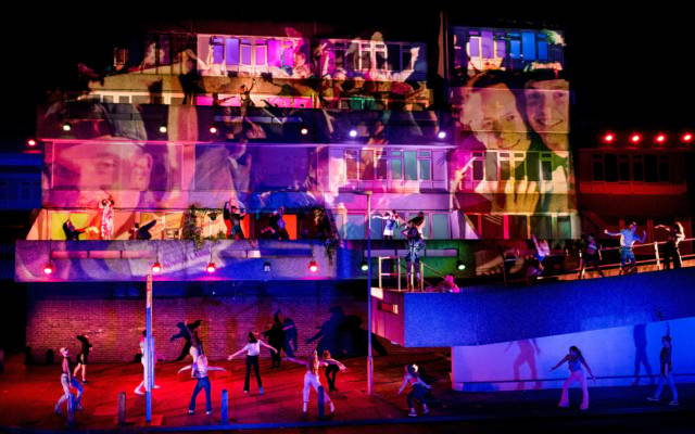 Beautiful Thing, Festival.org, Robbie Graham, GDIF 2018, Thamesmead. A concrete building is lit up with projections, dancers surround it and dance on the balconies.